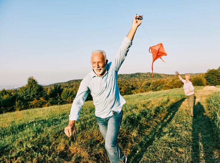 Ein Älteres, vitales Paar beim Drachensteigen. Sport verbessert die Mitochondrien Funktion, was zu mehr Energie & Vitalität führt